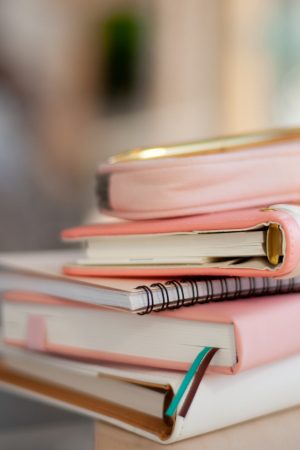 stylish designed coral and white coloured stack of diaries with gold pen. Organiser and planner addicted people. Choosing and sorting journals.
